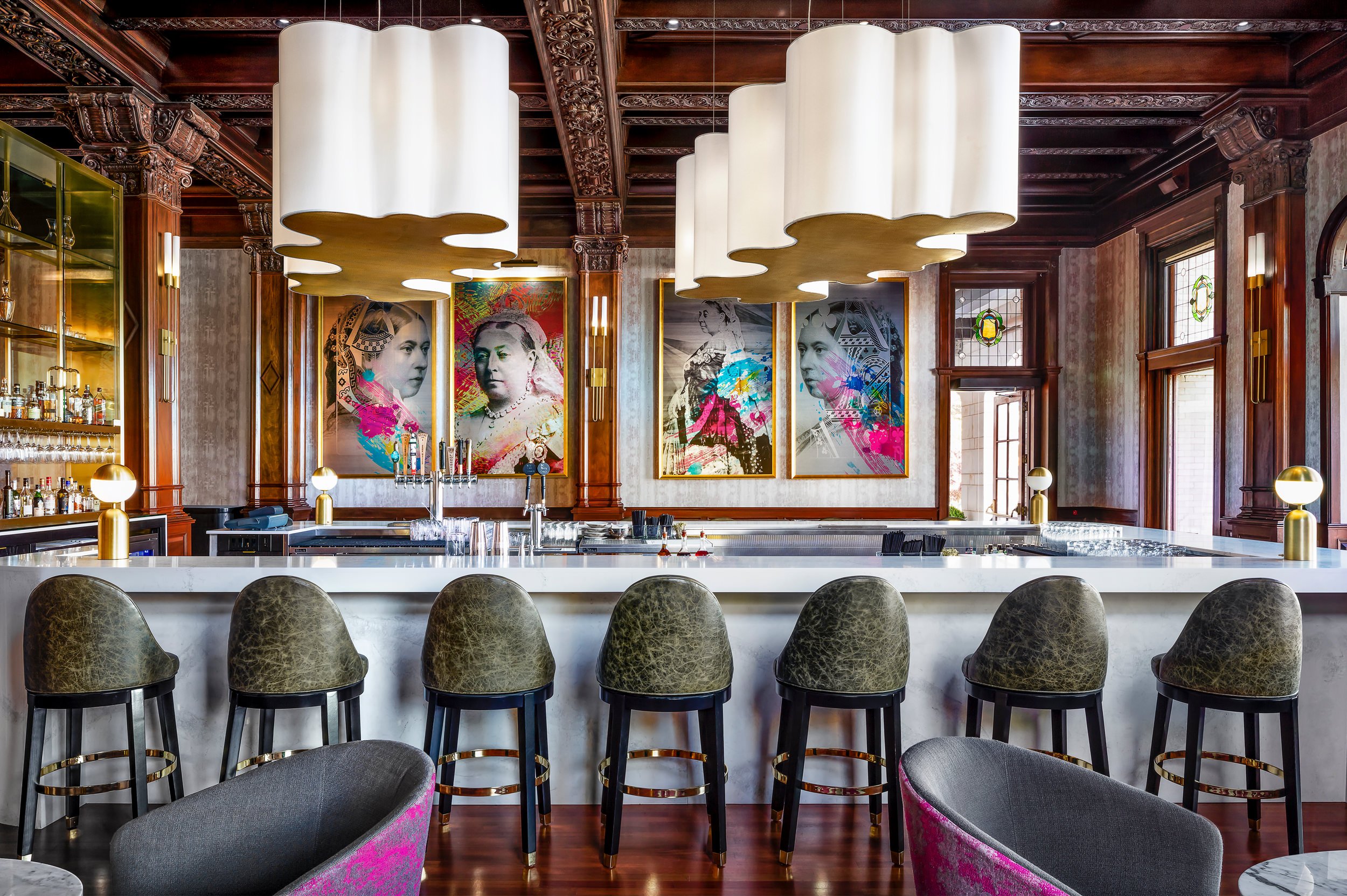 white bar with leacolourful framed portraits of Queen Victoria displayed behind a bar