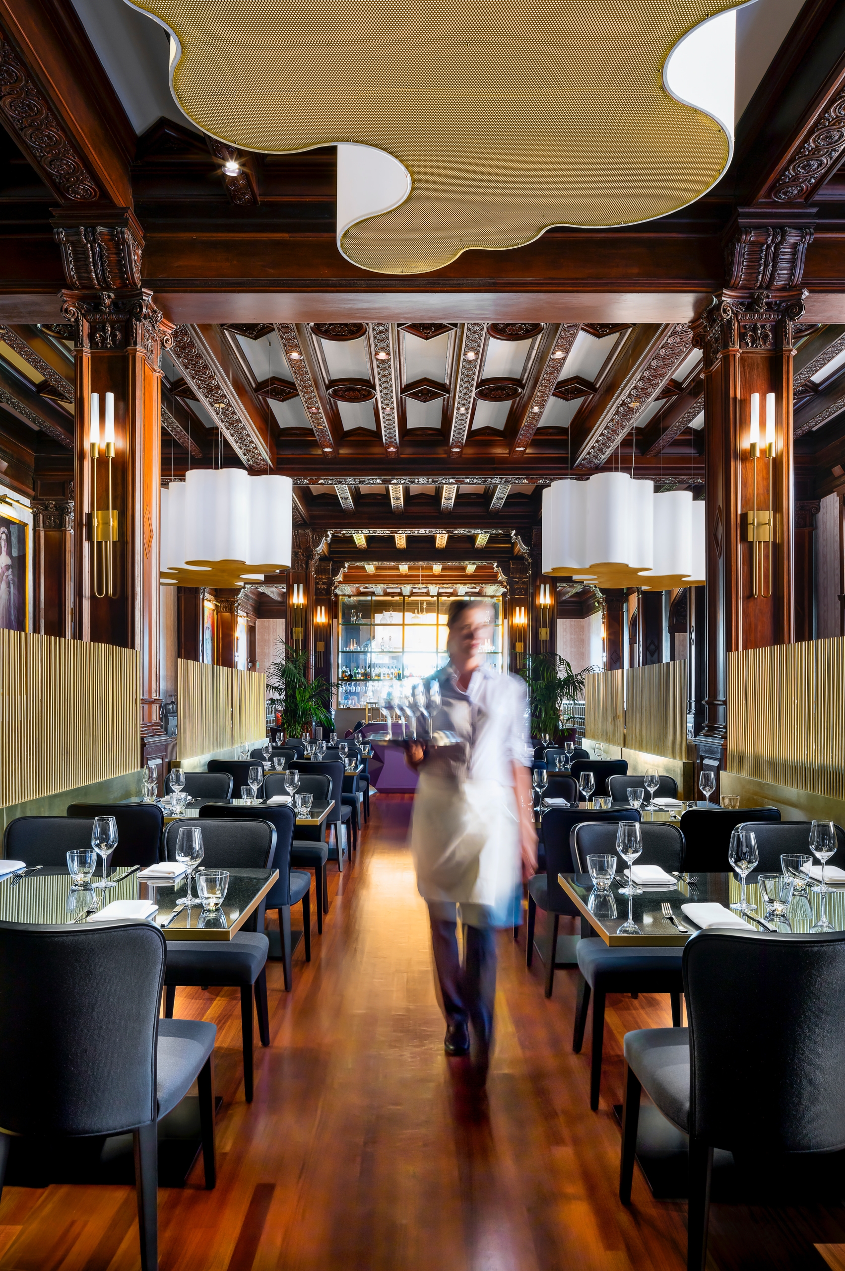 waiter carrying drinks through seating area of restaurant