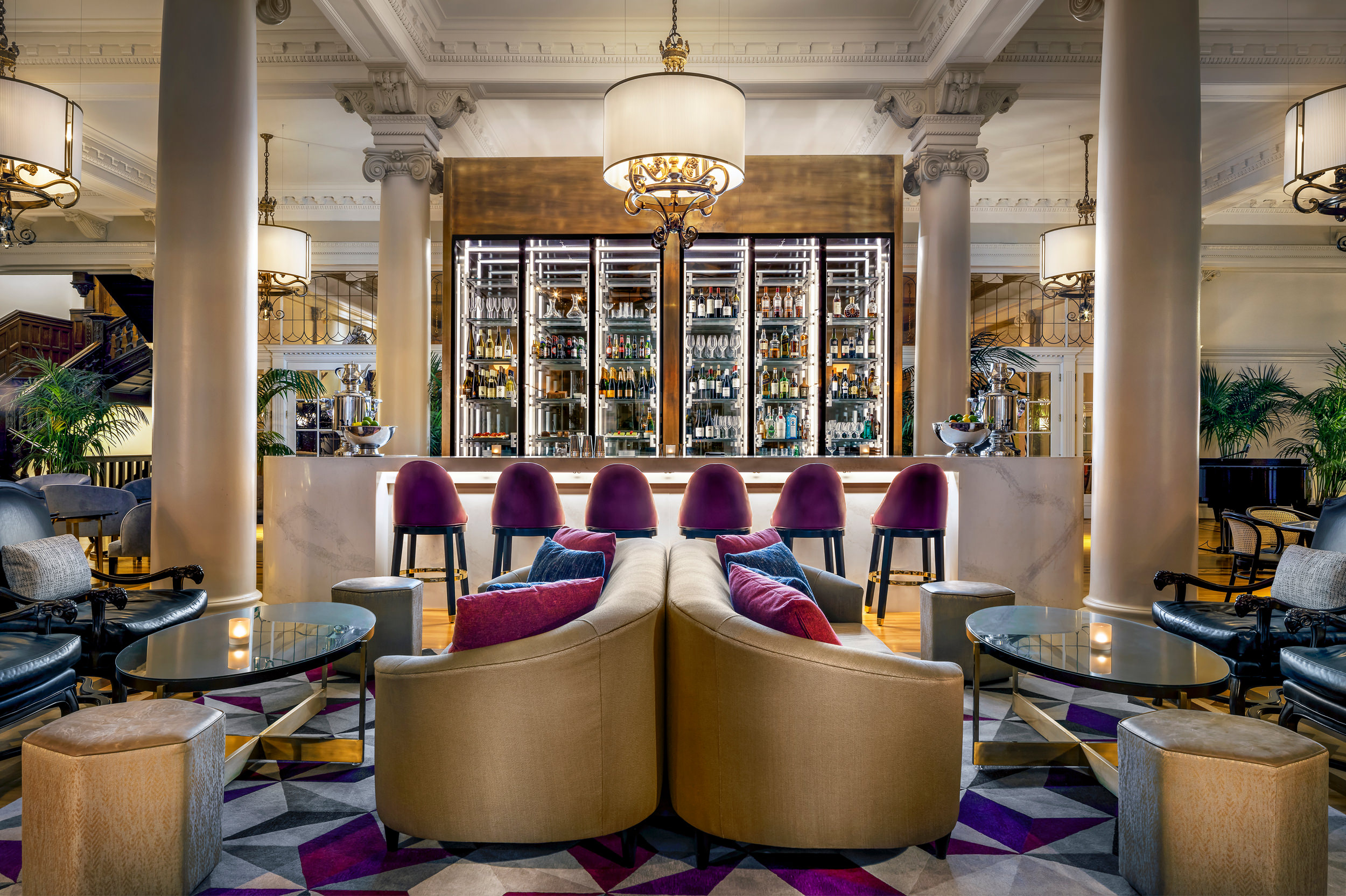 lounge with couches, armchairs and red stools set up at a bar