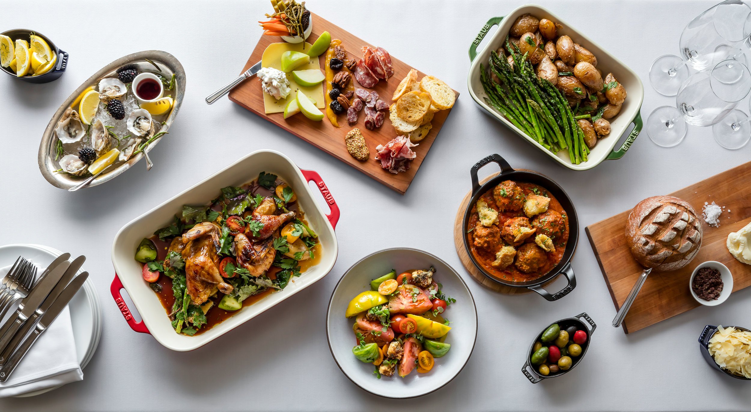 charcuterie board, meatballs, and two casserole dishes with roasted meat and vegetables