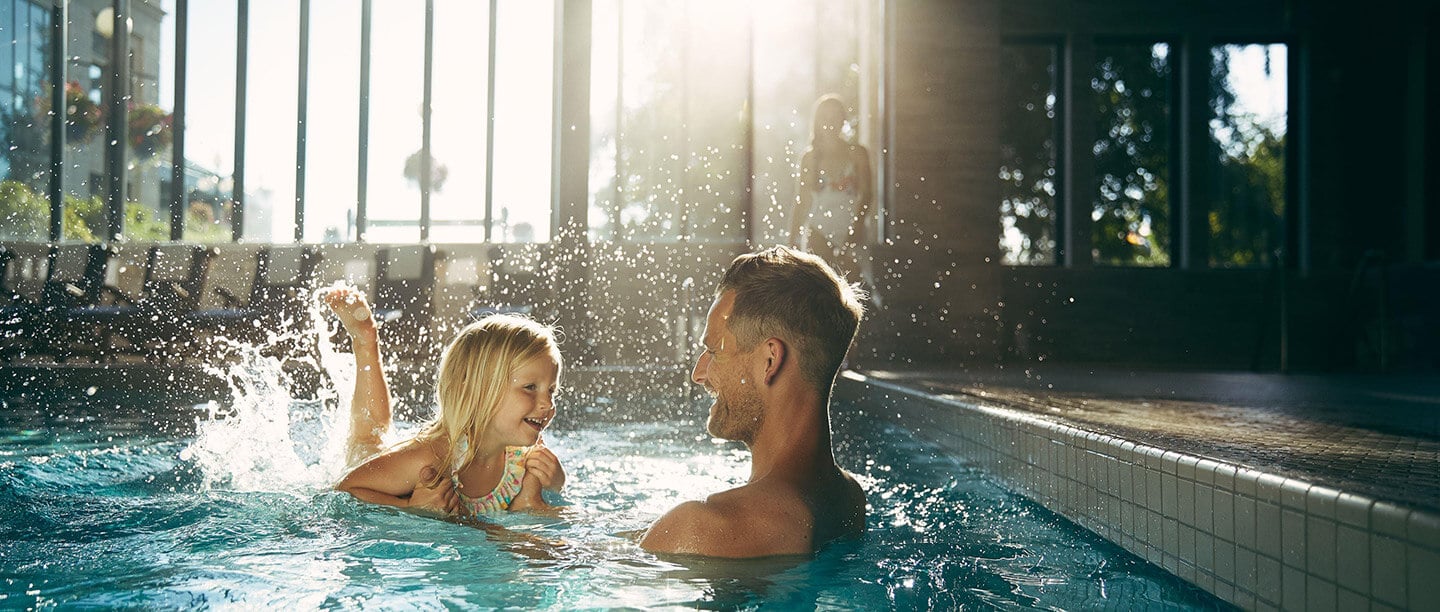 father and daughter in a pool swimming
