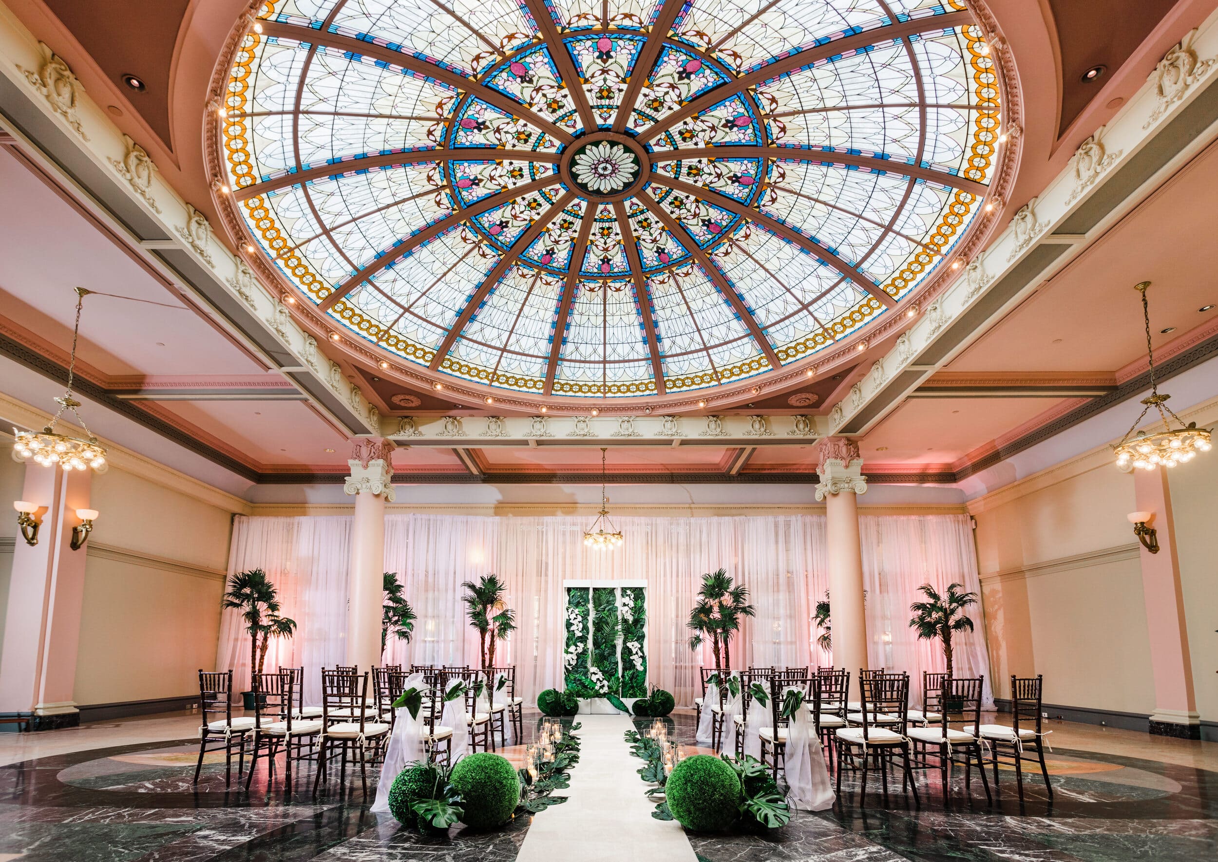 room with stain glass ceiling set up for a wedding